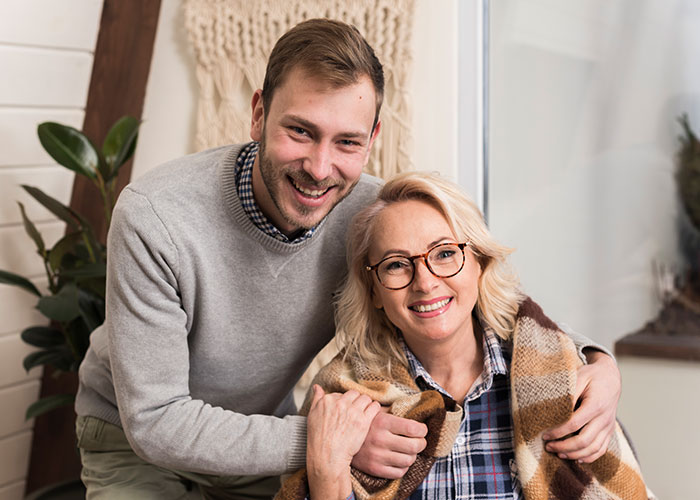 Hombre y mujer sonriendo en un entorno acogedor, representando secretos familiares.