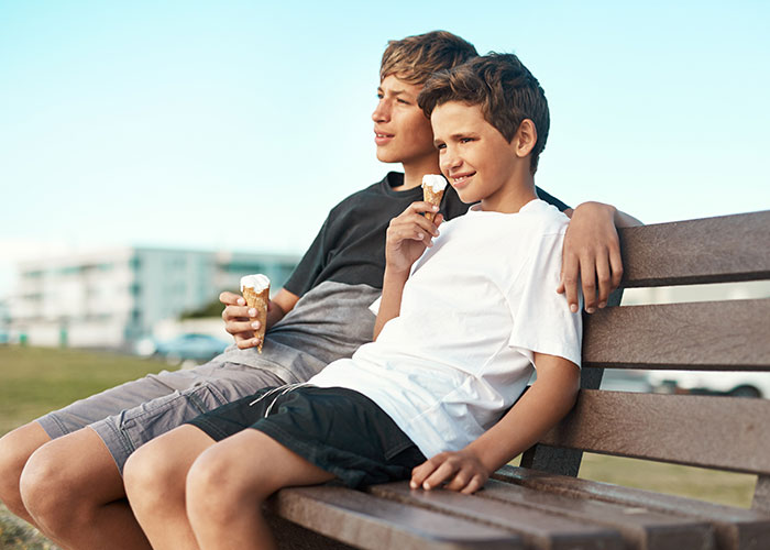 Niños comiendo helado en un parque, disfrutando un momento familiar.