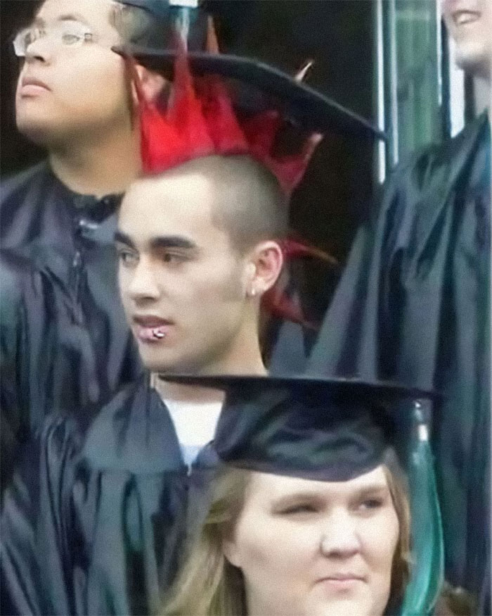 Estudiante en graduación con cresta roja, creando una imagen divertida e inusual en la ceremonia.