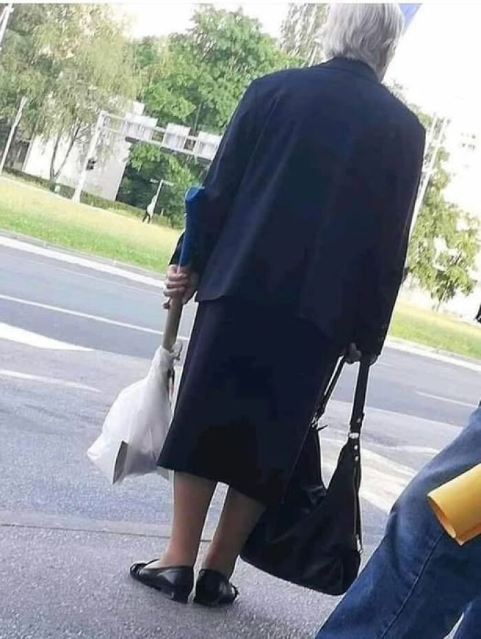 Persona con zapatos al revés, imagen rara y curiosa en la calle, frente a un parque.
