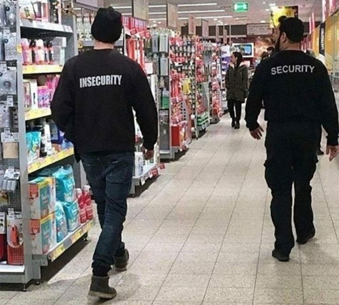 Dos hombres en un pasillo de tienda, uno con chaqueta "Insecurity" y otro "Security", imagen divertida y confusa.