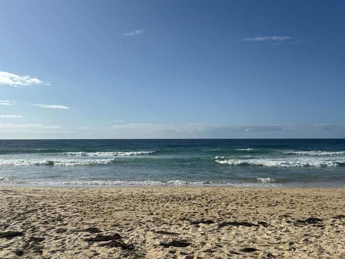 Playa australiana con arena dorada y olas suaves bajo un cielo despejado.