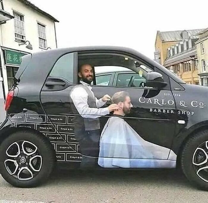 Coche pequeño con diseño creativo de barbería mostrando a un barbero cortando cabello, imagen divertida que causa risa.
