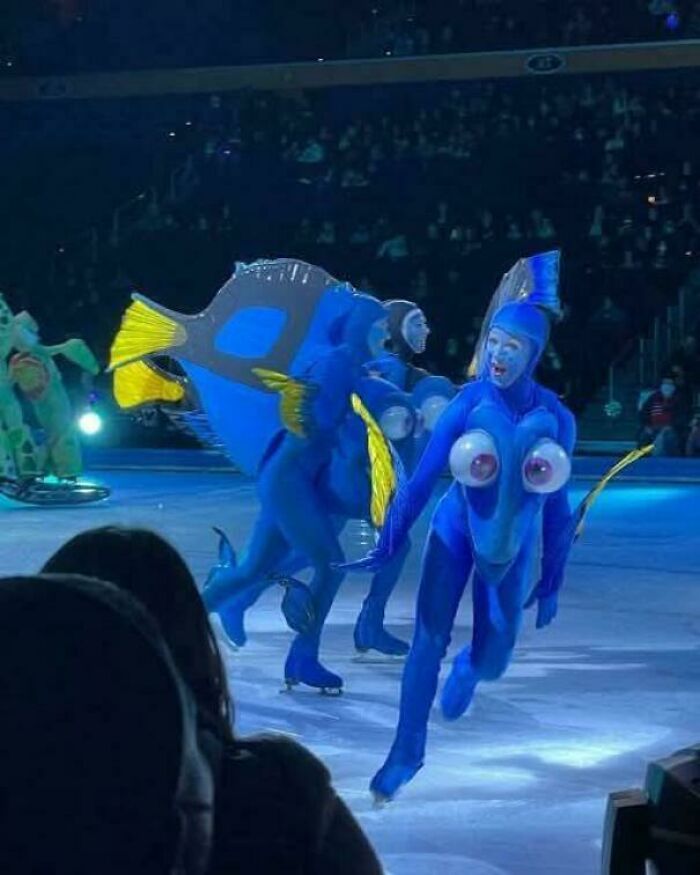 Personas con buenas habilidades en un espectáculo sobre hielo usando disfraces creativos de peces azules en escena.