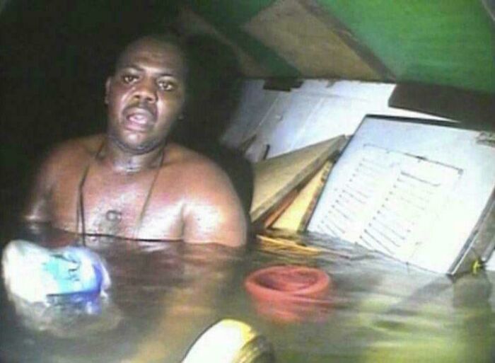 Hombre en una habitación inundada, sosteniendo una botella plástica, reflejando un suceso increíble.