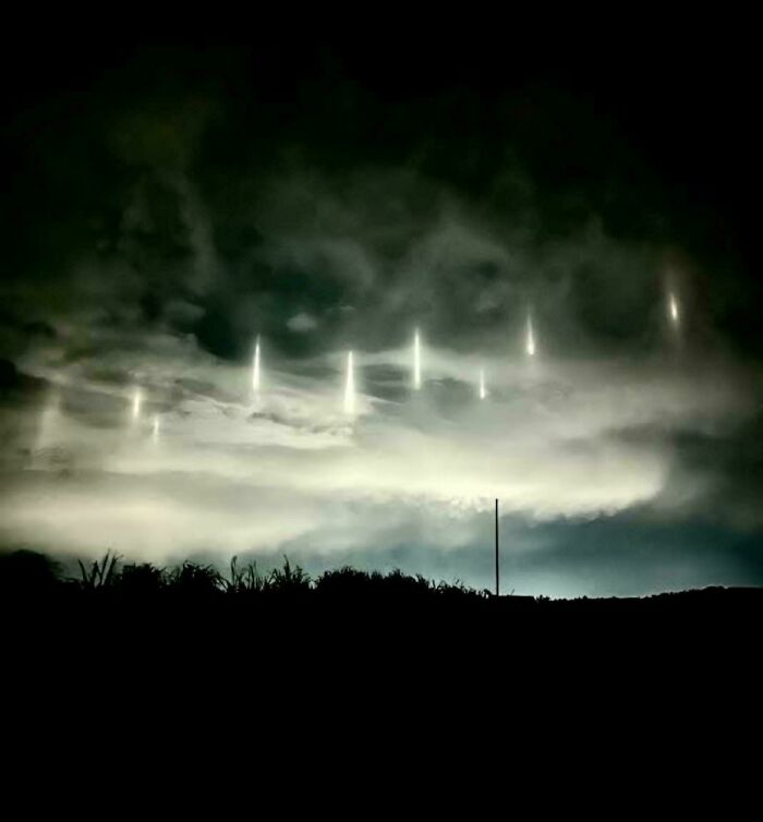 Cielo nocturno con extrañas luces verticales, creando una atmósfera inquietante y aterradora.