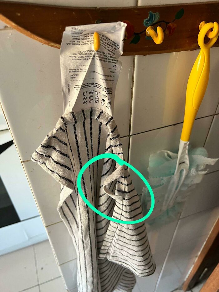 Toalla de cocina colgada incorrectamente por un marido, mostrando una etiqueta visible en el gancho.