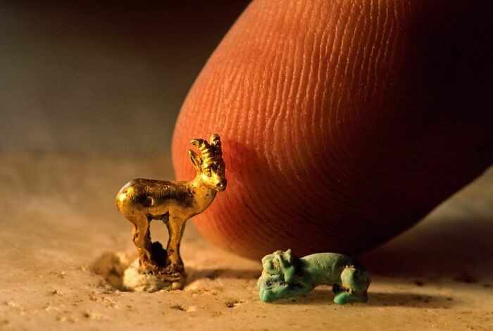 Miniatura de un cabrito dorado junto a una figura de cerámica verde, ejemplificando hallazgos fascinantes antiguos.