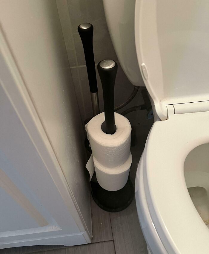 Papel higiénico enrollado en un soporte cerca del inodoro, ejemplo humorístico de comportamiento de hombres.