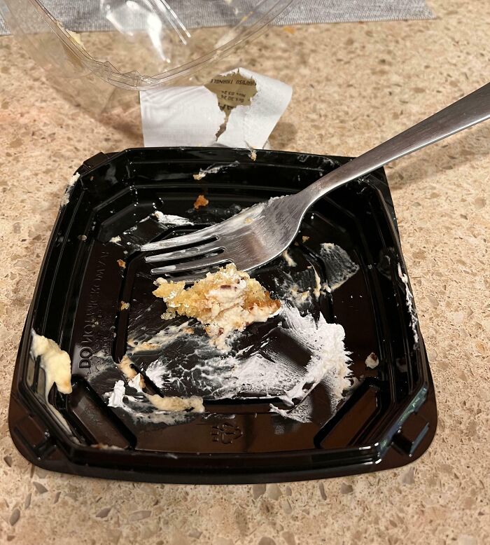 Restos de pastel en un plato de plástico con un tenedor sobre la mesa, ejemplo divertido de comportamiento de 