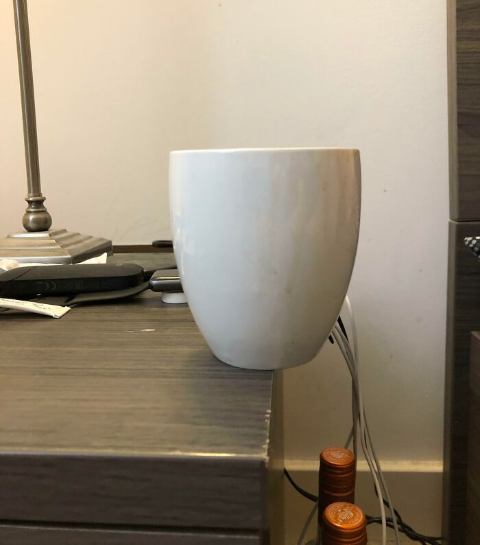 Taza blanca en una mesita con cables detrás, resaltando ejemplos de hombres en situaciones cotidianas.