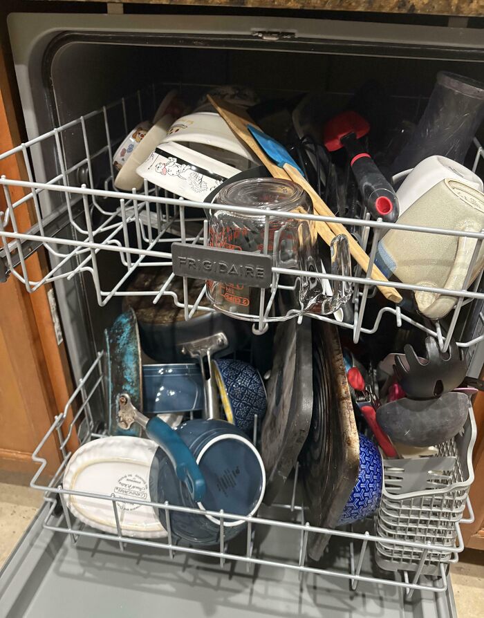 Lavavajillas lleno de utensilios y platos desordenados, resaltando comportamientos típicos de 