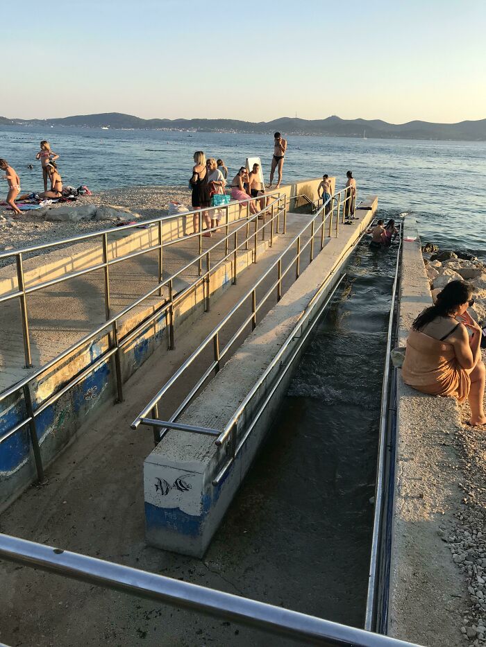 Personas disfrutando la playa y el mar en un muelle con accesos adaptados, una de las cosas que sorprendieron a los viajeros.