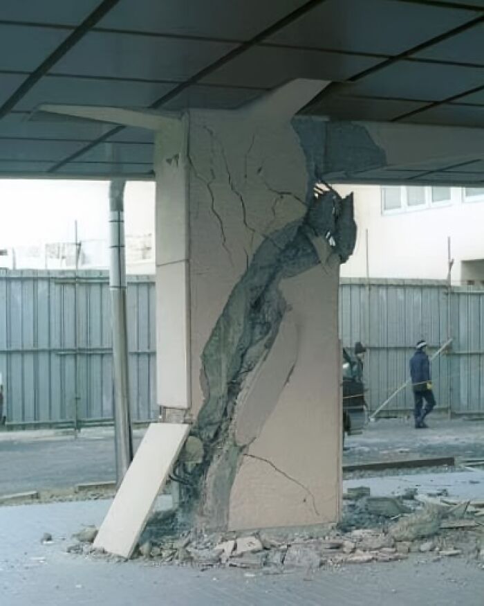Columna de arquitectura defectuosa con grietas visibles en un entorno urbano.