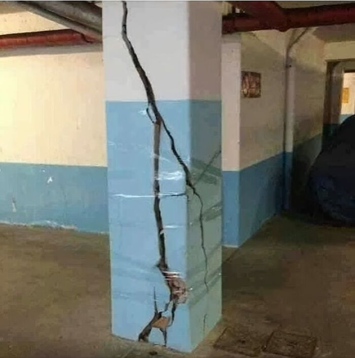 Columna agrietada en un sótano mostrando fallos de arquitectura.