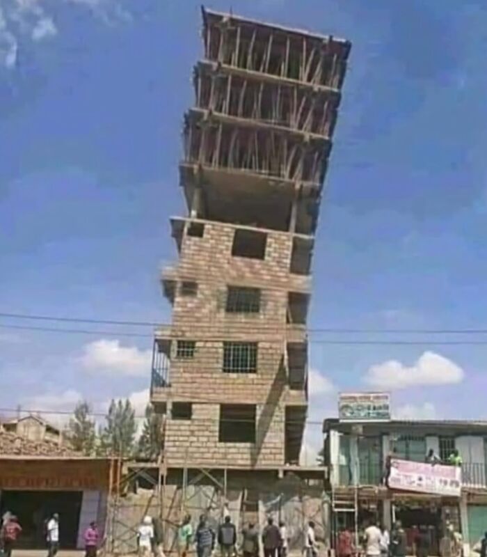 Edificio inclinado con fallos de arquitectura que resultan graciosos, varias personas observan en la calle.