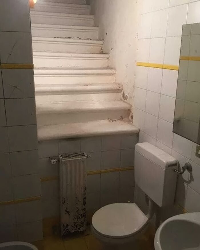 Baño con inodoro frente a una escalera, ejemplo de fallos de arquitectura.