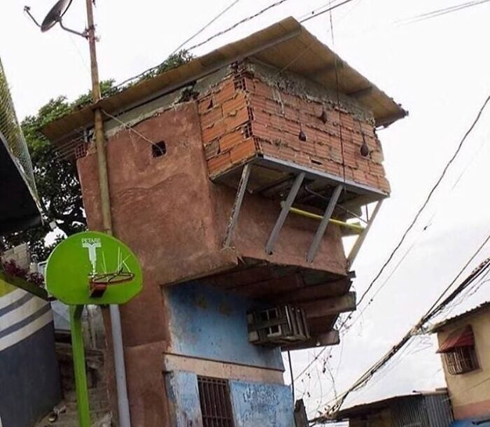 Edificio con fallos arquitectónicos, ladrillos expuestos y soporte inestable, causando una impresión humorística.