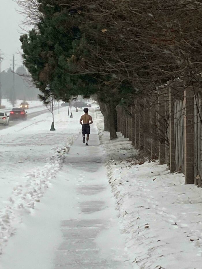 Corredor sin camiseta en una acera nevada en Canadá, mostrando una escena invernal curiosa.