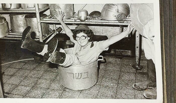 Niña sonriente dentro de una olla en cocina antigua, imagen fascinante de fotos históricas únicas y sorprendentes.
