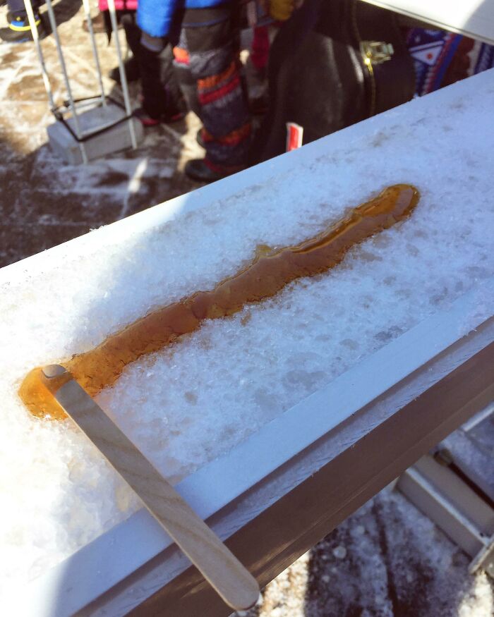 Palo de madera sobre nieve con jarabe de arce, representando una tradición curiosa de Canadá.