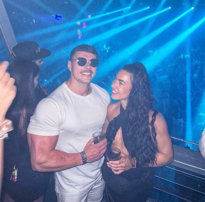 Pareja en una fiesta nocturna, reflejando la diferencia entre Instagram y realidad, con luces azules de fondo.