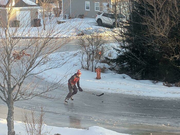 Hockey sobre hielo en una calle nevada de Canadá, representando la cultura y clima únicos del país.