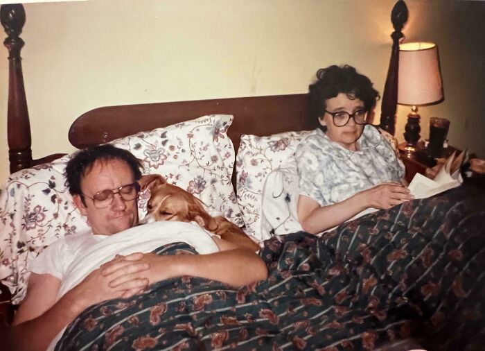 Pareja descansando en cama con perro pequeño, imagen familiar en casa, foto histórica fascinante y nostálgica.