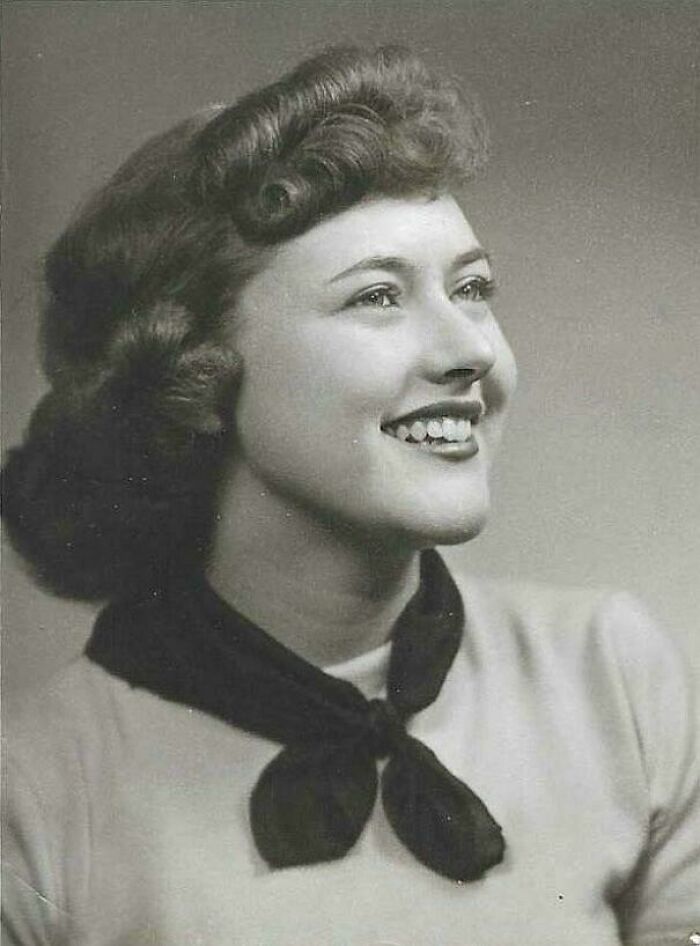 Retrato en blanco y negro de mujer sonriente con peinado clásico, ejemplificando fotos históricas fascinantes de época pasada.