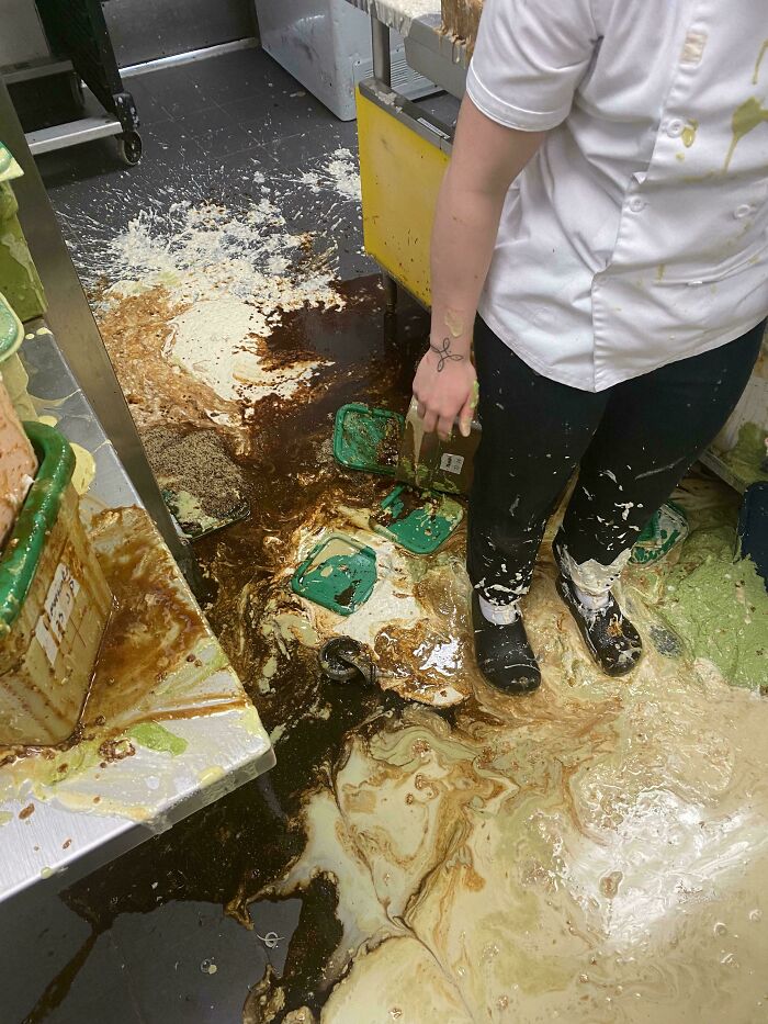 Empleado de hostelería en una cocina, con derrame de alimentos en el suelo, reflejando situaciones frustrantes comunes.