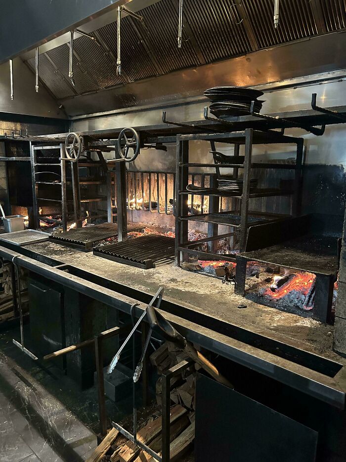 Cocina industrial en hostelería con parrillas y brasas, mostrando condiciones de trabajo desafiantes.