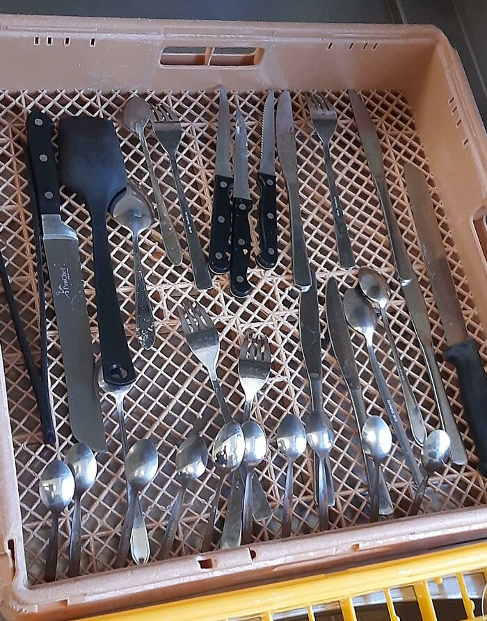 Cubiertos de hostelería colocados en una bandeja marrón, listos para su uso en restaurante.