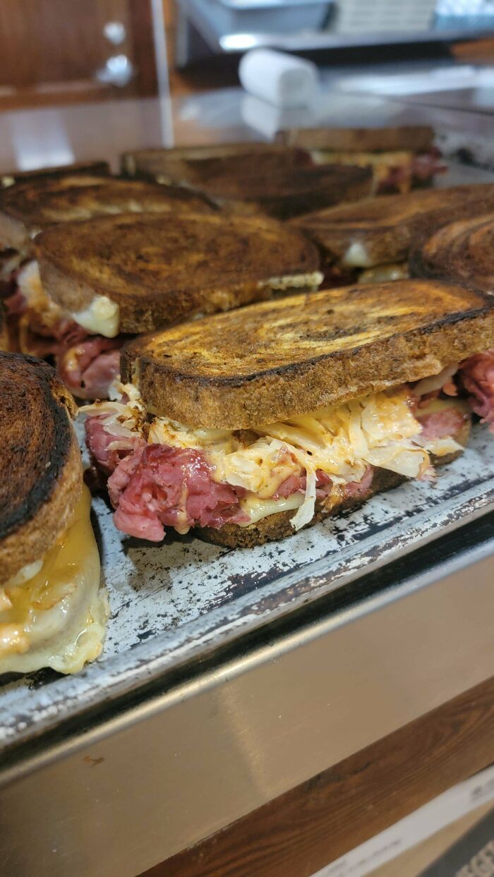 Sandwiches tostados de carne y queso sobre bandeja de metal, situación común en hostelería.