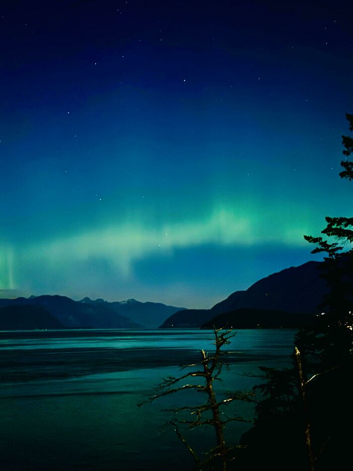 Aurora boreal sobre un paisaje montañoso en Canadá, capturando la belleza natural del país.