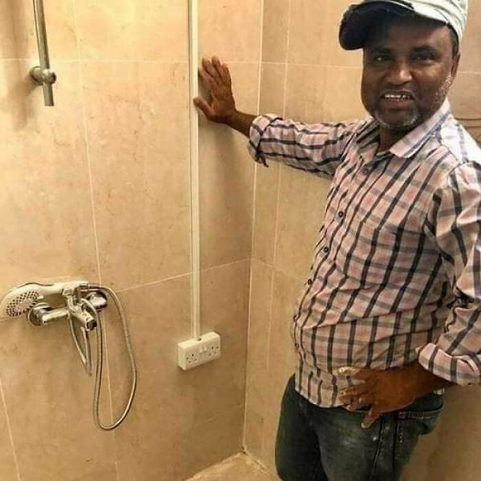 Hombre junto a un enchufe eléctrico en ducha, ejemplo de fallos de arquitectura.