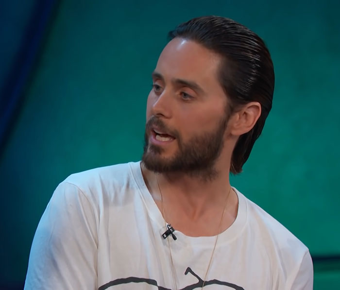 Actor en una entrevista, con cabello recogido y barba, hablando sobre historias de comportamiento.