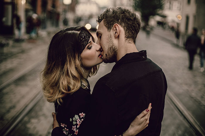 Pareja besándose apasionadamente en la calle, escena romántica como en los libros.