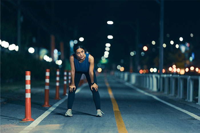 Mujer haciendo ejercicio en la calle, vestida de azul, tomada por la noche, simbolizando momentos para irse.