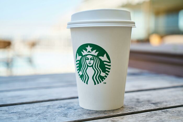 Vaso de café Starbucks sobre una mesa de madera, ideal para acompañar conversaciones interesantes.