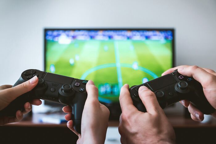 Manos jugando videojuegos en un televisor, usando controles mientras disfrutan de una conversación emocionante.