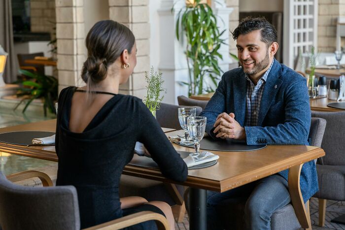 Pareja conversando en un restaurante elegante, ilustrando conversaciones escuchadas casualmente.