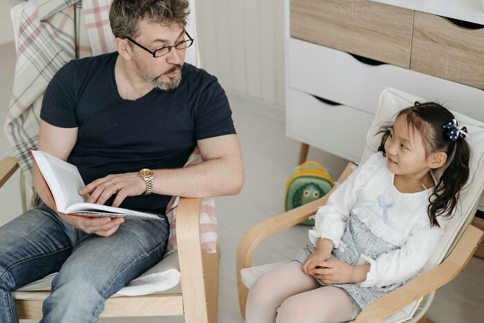 Hombre leyendo a una niña en una conversación divertida.