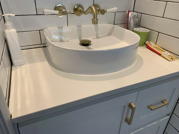 Lavabo con grifos dorados en baño moderno, ejemplo de interiorismo poco práctico.