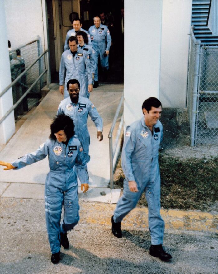 Astronautas caminando en fila vestidos con trajes azules, parte de una historia inquietante detrás de su misión.