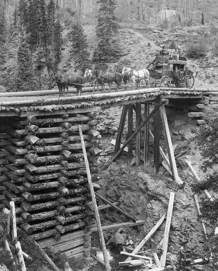 Carruaje tirado por caballos cruzando un puente de madera en una imagen histórica poco conocida.
