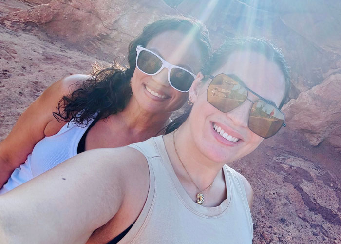 Two best friends smiling in sunglasses at a sunny outdoor location.