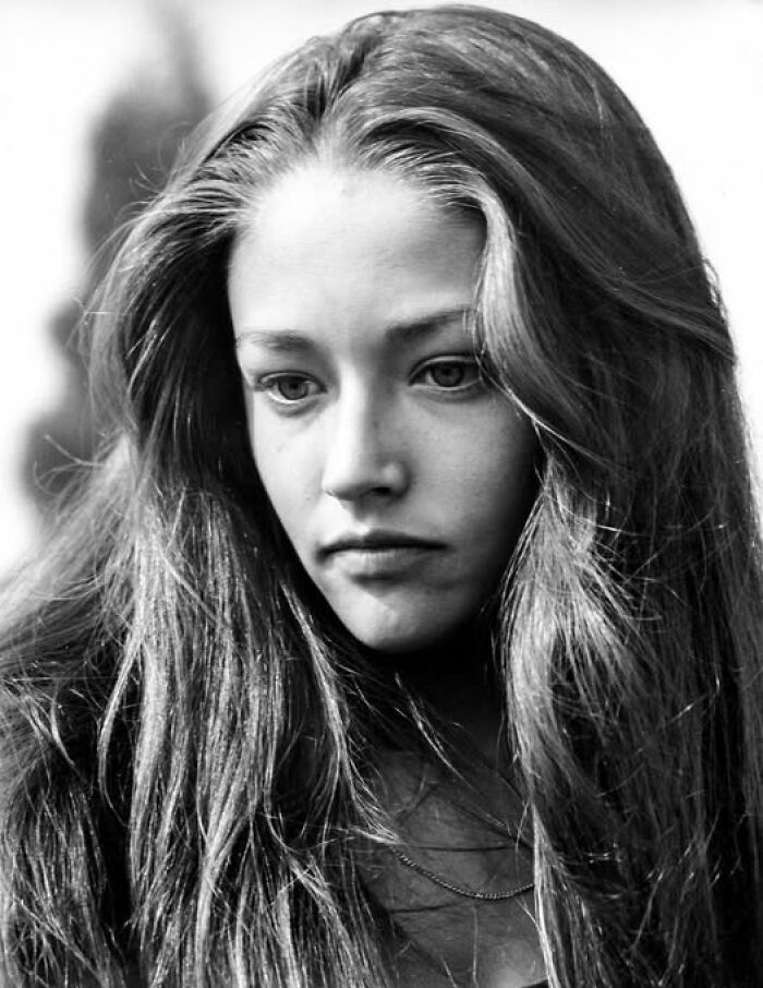 "Mujer joven en foto histórica en blanco y negro, cabello largo y expresiva mirada."