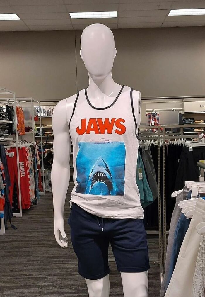 Maniquí con camiseta de Jaws, representando imágenes raras y absurdas en tienda de ropa.