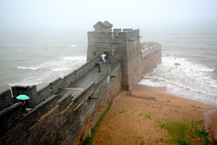 Perspectiva única de una muralla antigua junto al mar en día lluvioso, destacando lugares conocidos.