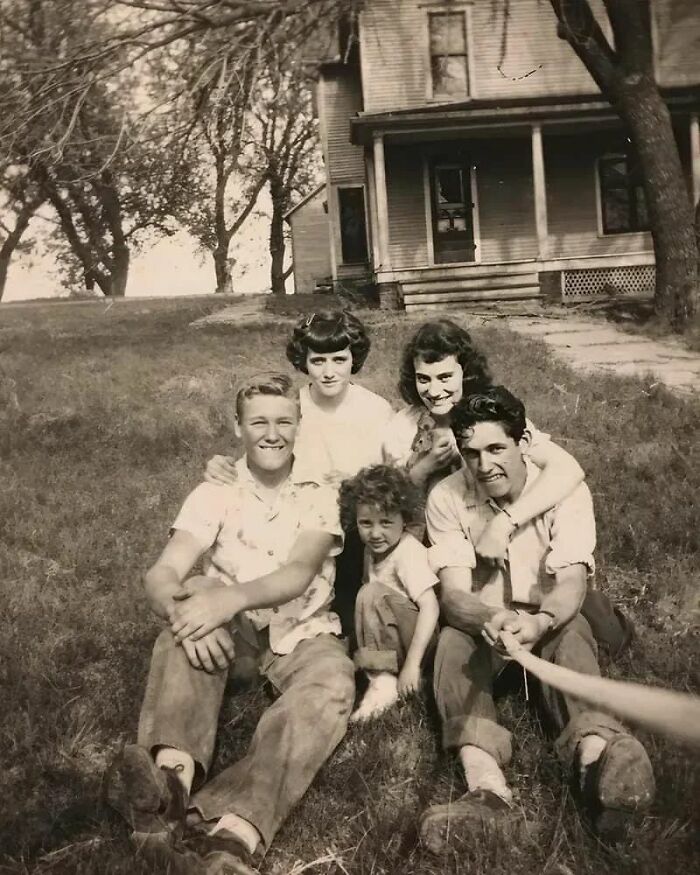 Familia posando en el césped frente a una casa antigua, recordando momentos históricos poco conocidos.